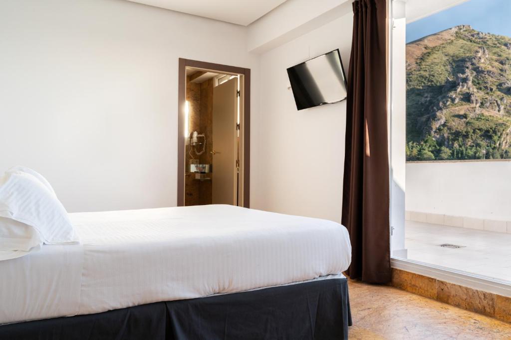 sypialnia z dużym białym łóżkiem i oknem w obiekcie Hotel Ciudad de Cazorla w mieście Cazorla