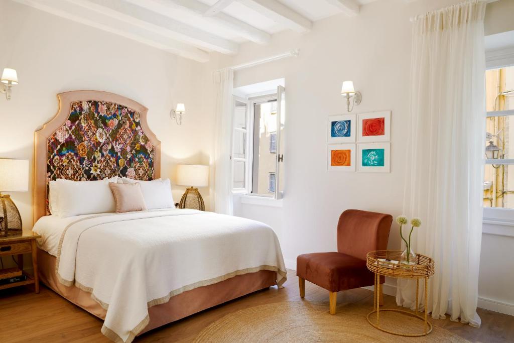 een witte slaapkamer met een groot bed en een stoel bij Old Town Luxury Suites 'Contessa' in Ágios Rókkos