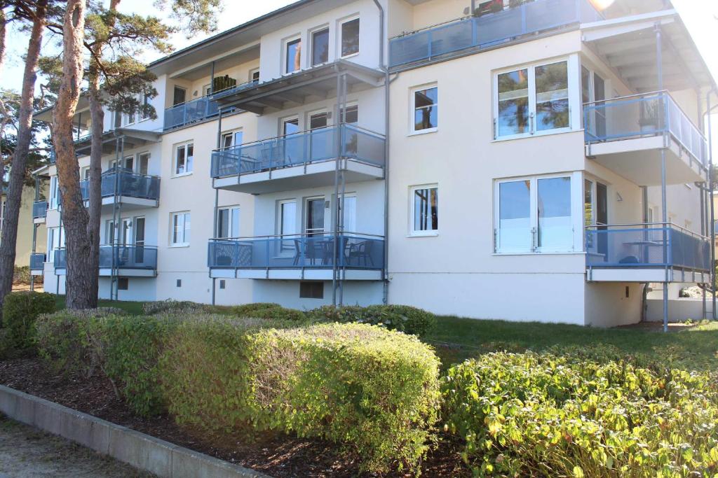 ein Apartmenthaus mit Balkonen und Büschen in der Unterkunft Ferienwohnung "Schwanenwiek" in Lubmin