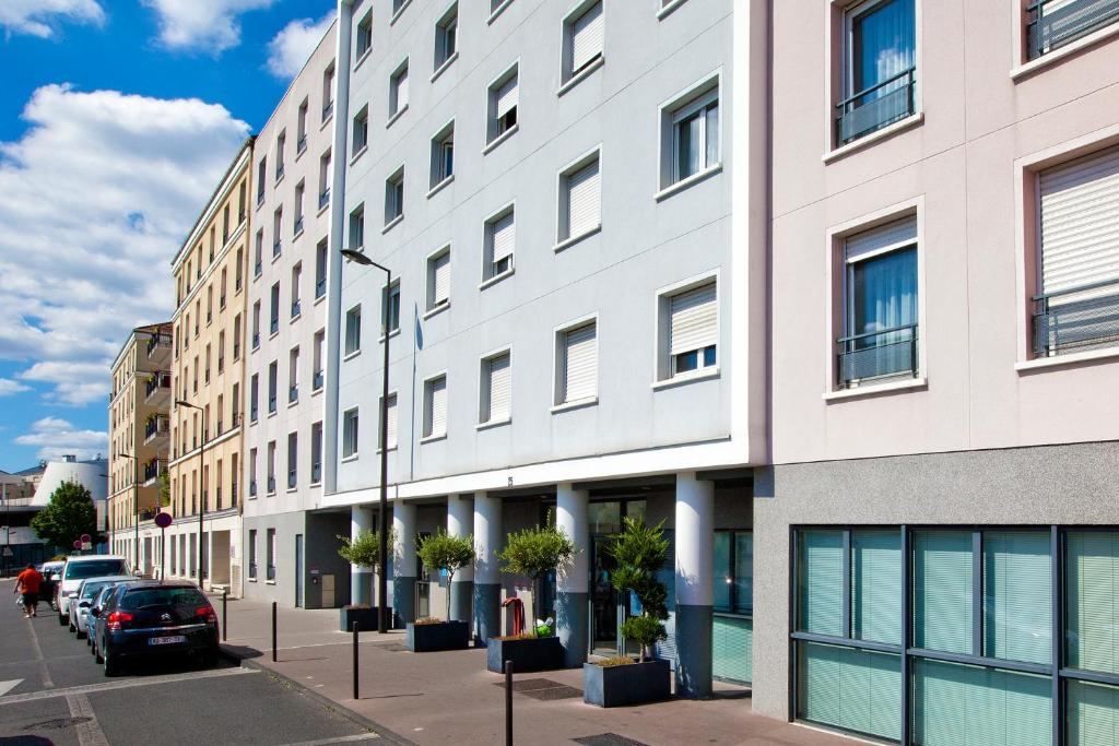 a building on a street with cars parked in front of it at Séjours & Affaires Paris Vincennes in Vincennes