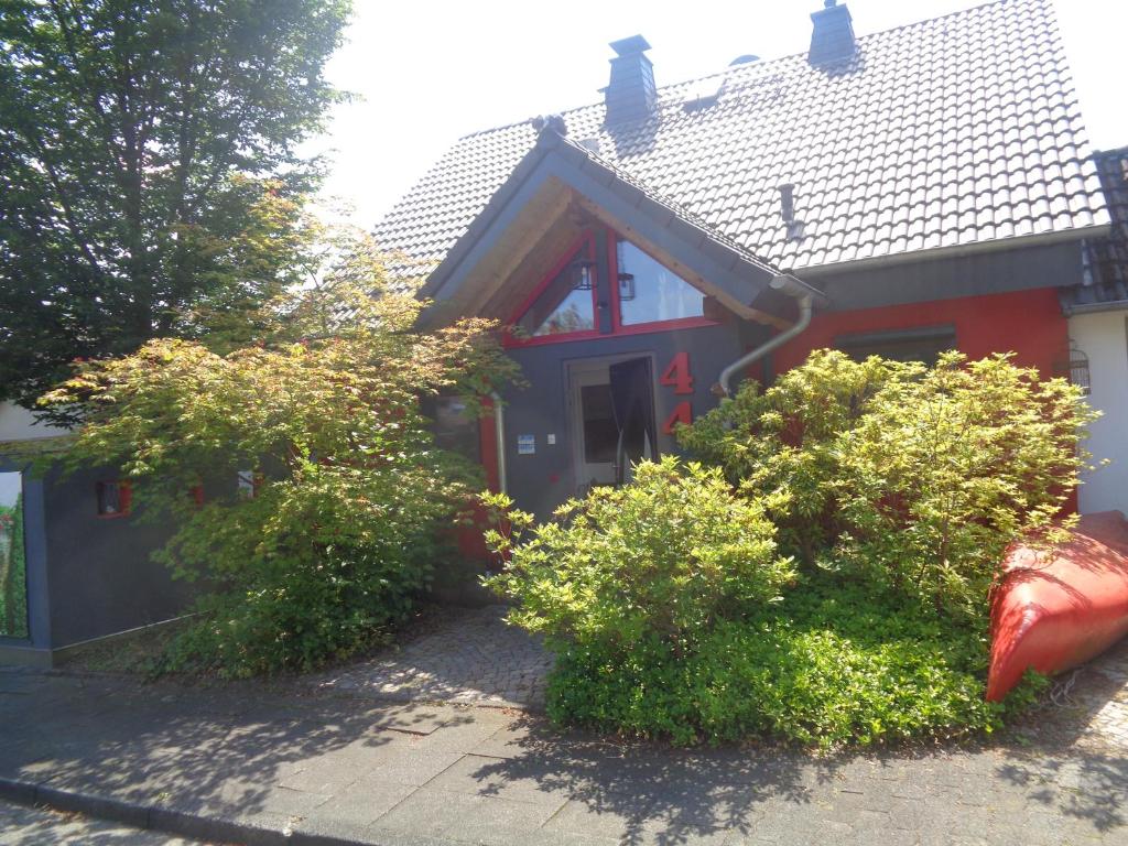 una casa roja con arbustos delante de ella en Ferienwohnung Carmen en Siegen