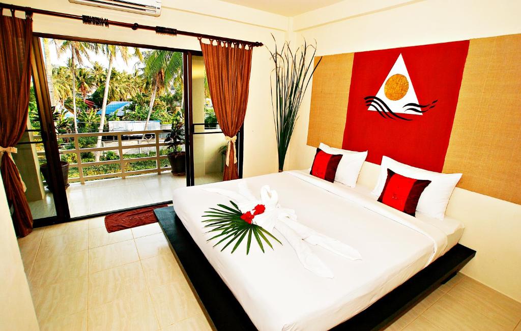 a bedroom with a large white bed with a flower on it at Aloha Lanta in Ko Lanta