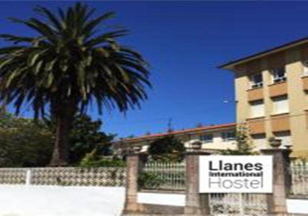 ポオ・デ・リャネスにあるLlanes International Hostelの椰子の木と建物前の看板