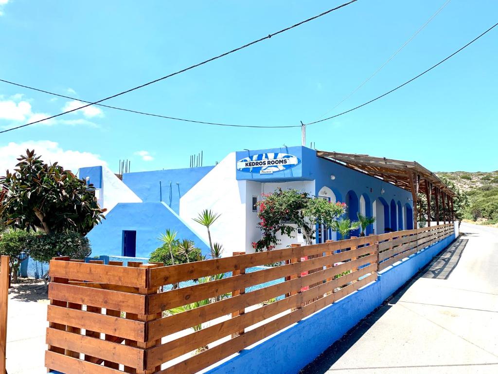 a blue building with a wooden fence in front of it at Kedros Rooms in Prasonisi