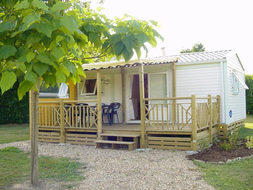 a tiny house with a porch and a deck at Camping de Marcilly sur Vienne in Marcilly-sur-Vienne