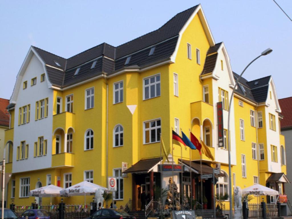 un grand bâtiment jaune avec un toit noir dans l'établissement Hotel Karlshorst, à Berlin