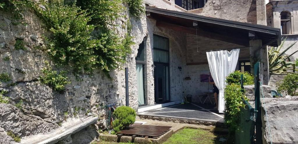 ein Steinhaus mit einer Bank und einem Regenschirm in der Unterkunft Casa Limonaia San Rocco in Limone sul Garda