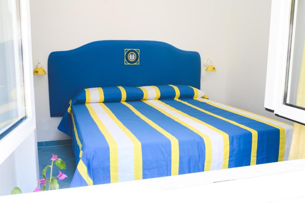 a blue bed with a blue and yellow striped blanket at Parco Augusto in Capri