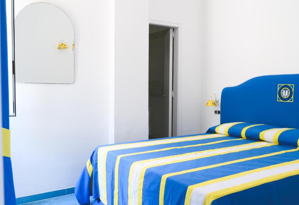 a blue bed with a blue and yellow striped blanket at Parco Augusto in Capri