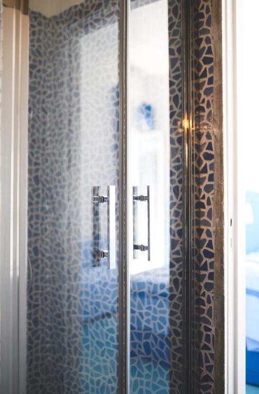 a bathroom with a glass shower with blue tiles at Parco Augusto in Capri