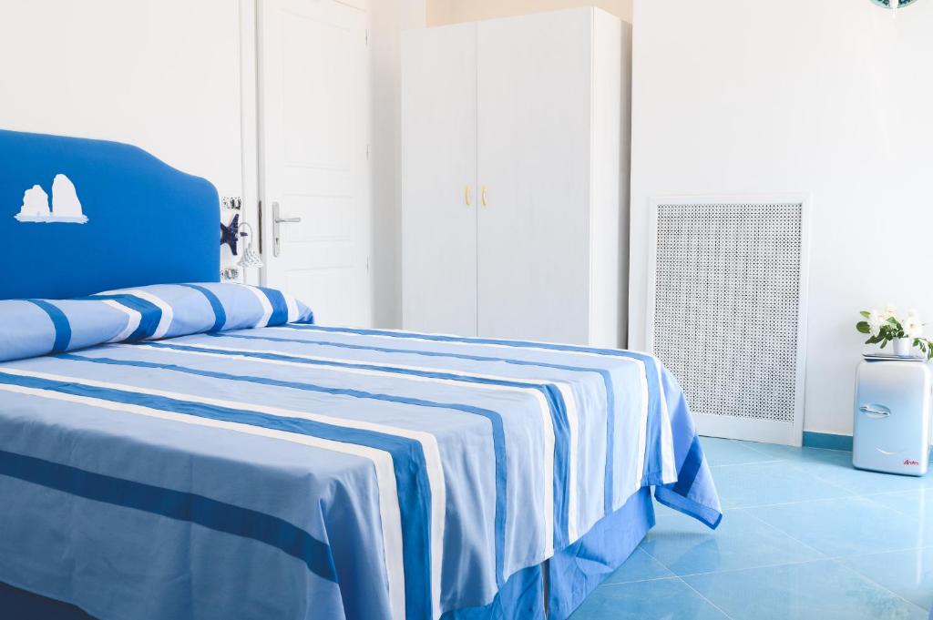 a blue bed with a blue and white striped blanket at Parco Augusto in Capri