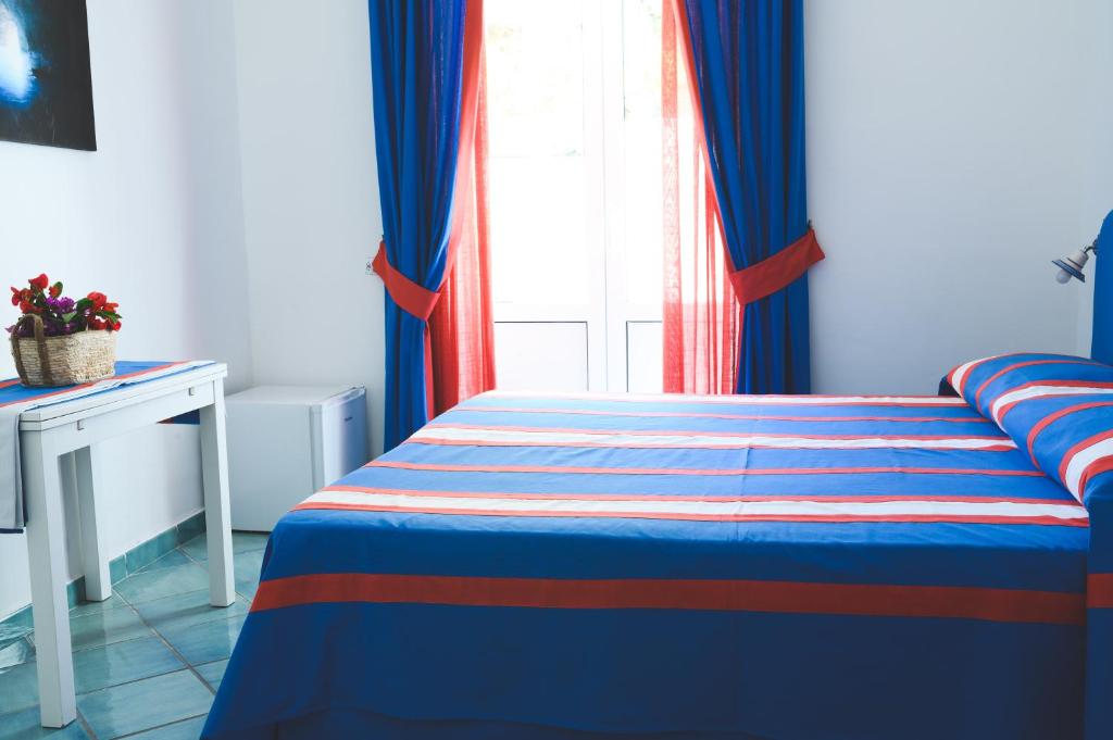a bedroom with a bed with blue curtains and a window at Parco Augusto in Capri