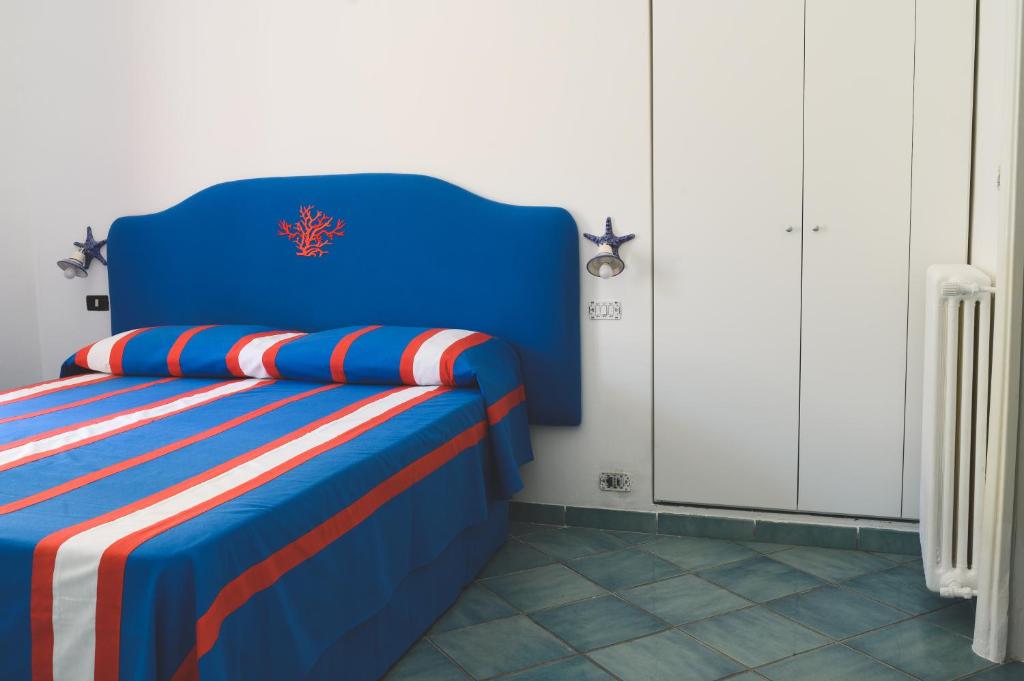 a blue bed with red and white pillows on it at Parco Augusto in Capri