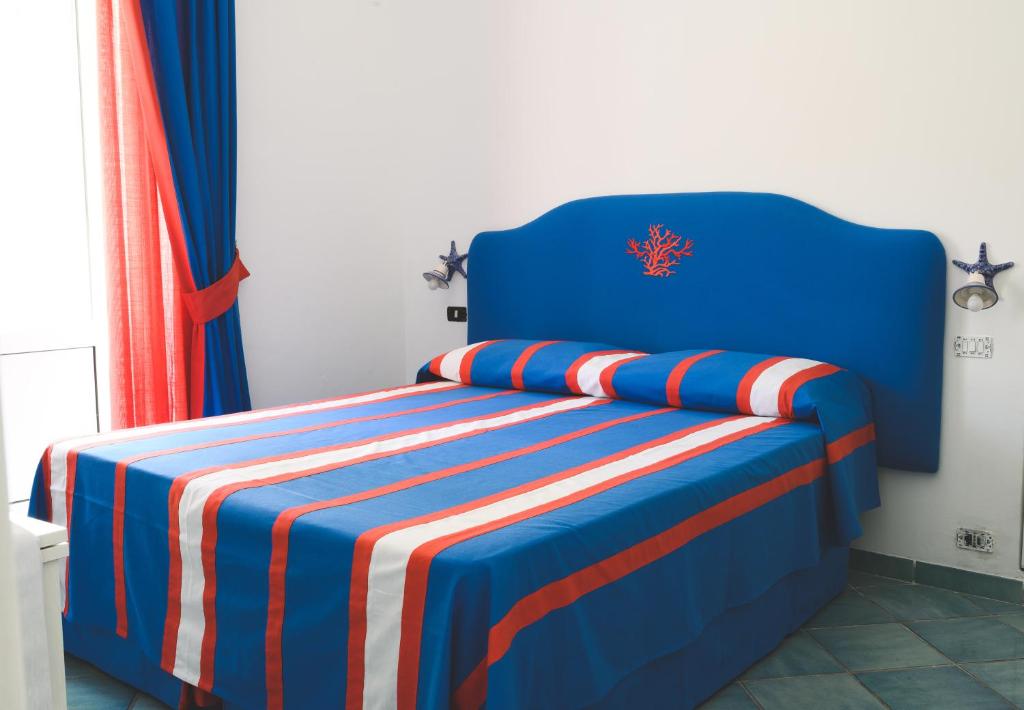 a blue bed with red white and blue sheets at Parco Augusto in Capri