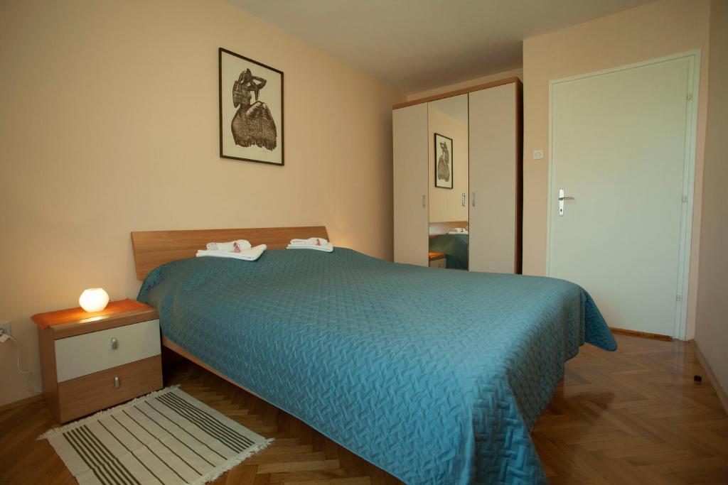 a bedroom with a bed with a blue bedspread at 10 minutes walk to the lakes in Plitvička Jezera