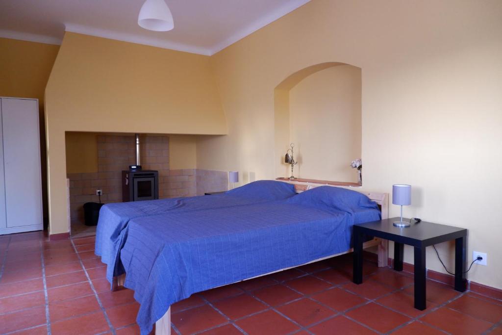 a bedroom with a blue bed and a table at Horta de Pepinais in Elvas
