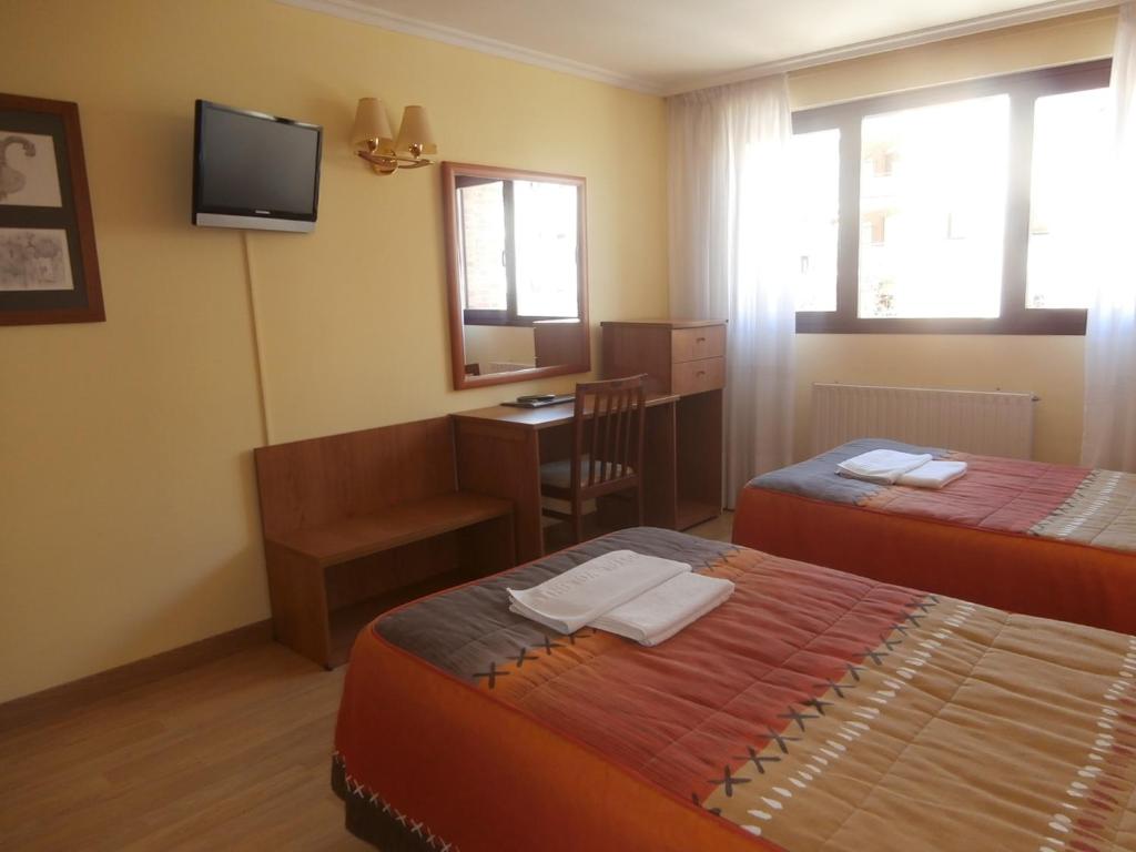 Zimmer mit 2 Betten, einem Schreibtisch und einem Spiegel in der Unterkunft Hostal El Volante in Estella