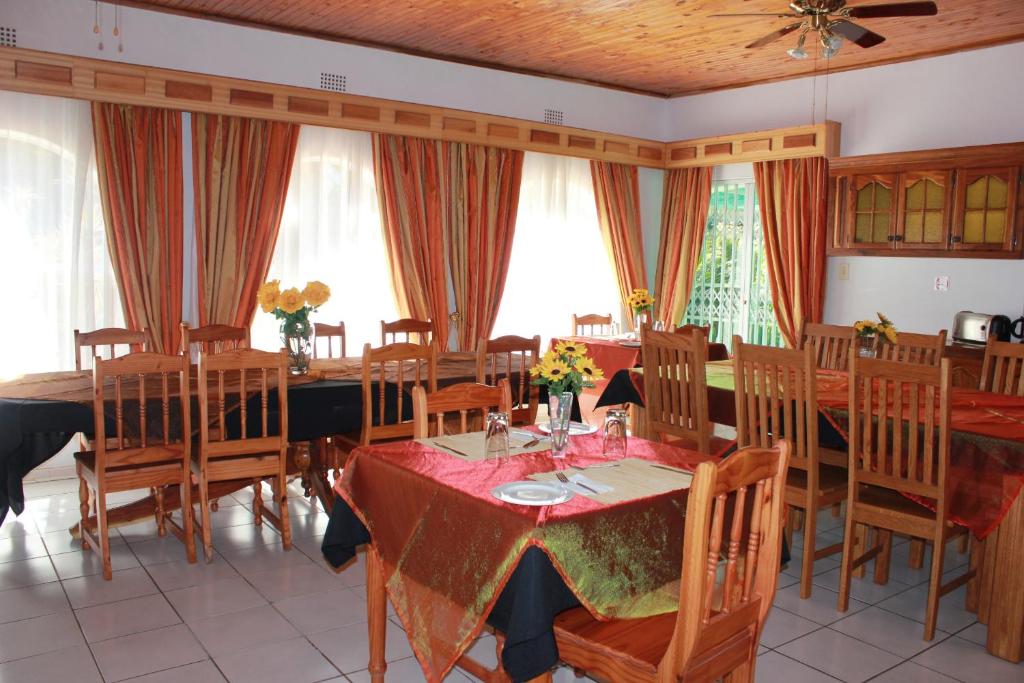 een eetkamer met tafels, stoelen en ramen bij El Palmar Guesthouse in Groblersdal