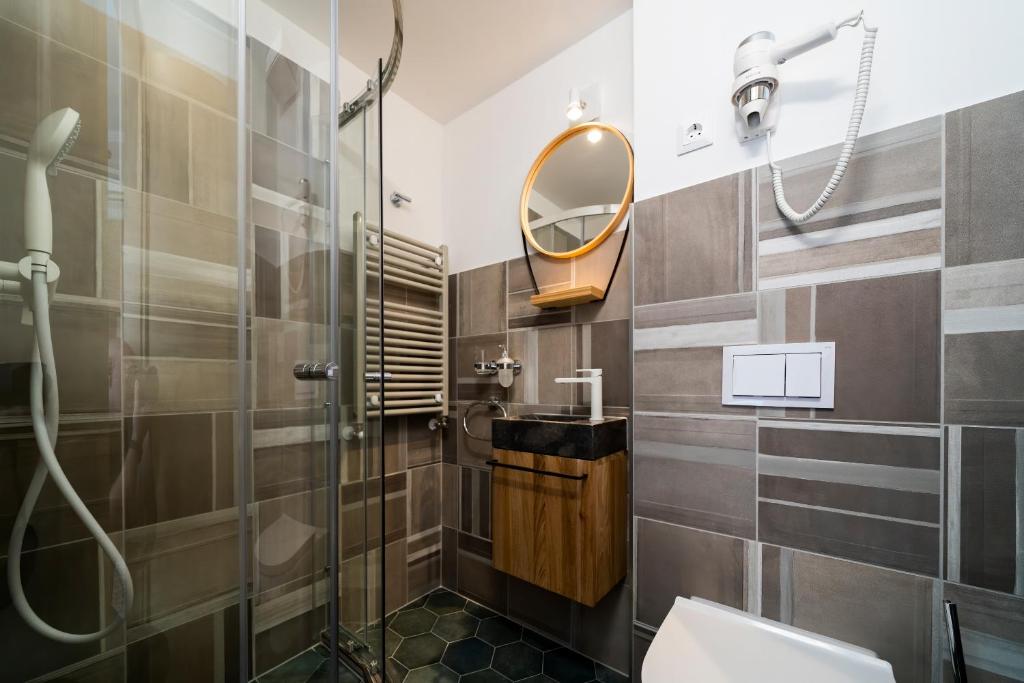W łazience znajduje się prysznic, toaleta i lustro. w obiekcie Duett - Urban Rooms w Győr
