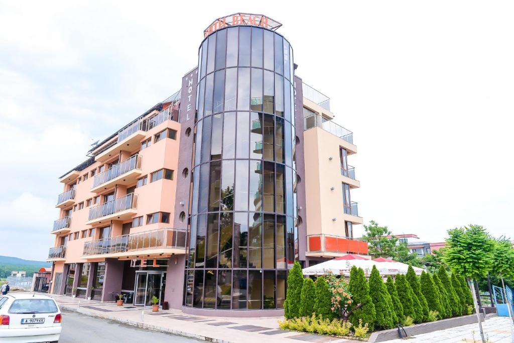 un edificio de cristal con un coche aparcado delante de él en North Beach Hotel, en Primorsko