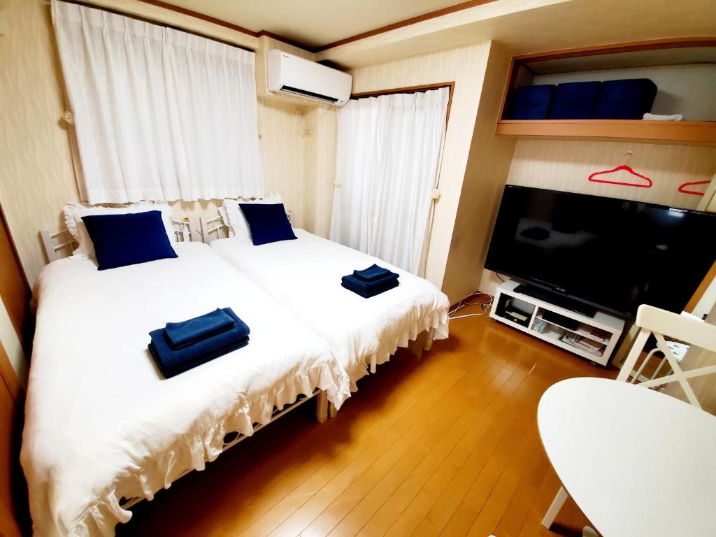 een slaapkamer met een bed en een flatscreen-tv bij Takaraboshi room 101 Sannomiya10min in Kobe