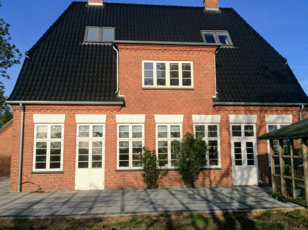 dom z czerwonej cegły z czarnym dachem w obiekcie Bed & Kitchen „Den gamle Skole“ Nr. Sejerslev w mieście Højer