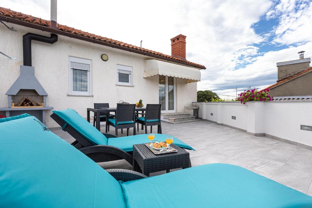 a patio with a blue couch and chairs and a table at Apartment Ivan in Sveti Ivan Dobrinjski