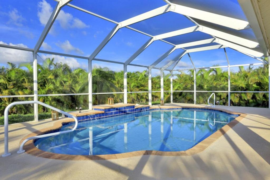 a large swimming pool with an umbrella over it at Villa Valmora in Cape Coral