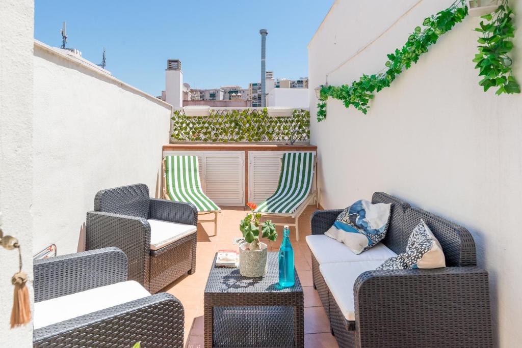 un patio con sillas de mimbre y una mesa en LU&CIA PENTHOUSE, en Málaga