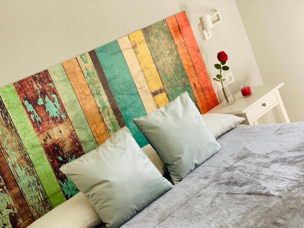 a bed with two pillows and a colorful wall at Atico Loft The Rose 48 in Cádiz