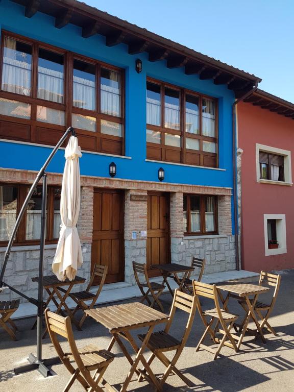 un grupo de mesas y sillas frente a un edificio en apartamentos rurales marrubiu-playa de Poo, en Llanes