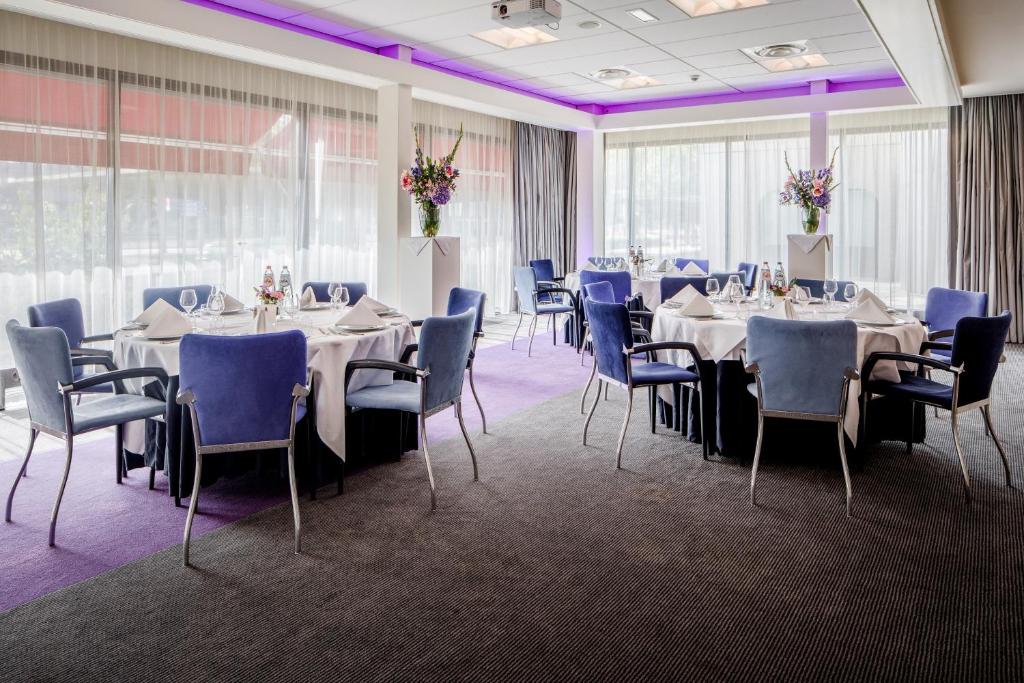 una sala de banquetes con mesas, sillas e iluminación púrpura en Holiday Inn Eindhoven Centre, an IHG Hotel, en Eindhoven