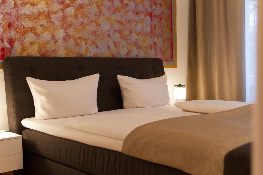 a bedroom with a bed with white pillows and a painting at Hotel Spreewitz am Kurfürstendamm in Berlin