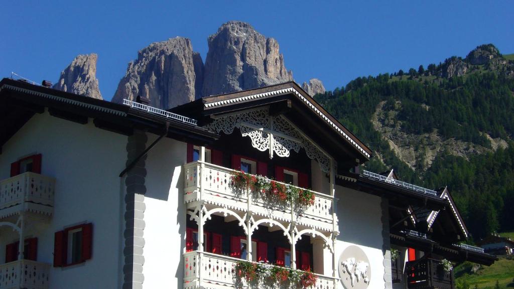 Un bâtiment avec des fleurs et une montagne dans l'établissement Villa Kofler Wonderland Resort, à Campitello di Fassa