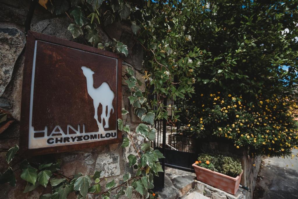 a sign on the side of a wall with plants at Hani Chrysomilou in Kalopanayiotis