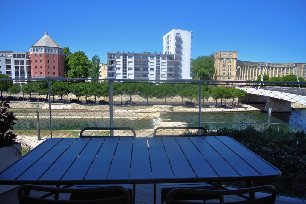 a picnic table on a balcony with a view of a river at Arbre Blanc, une folie montpelliéraine in Montpellier