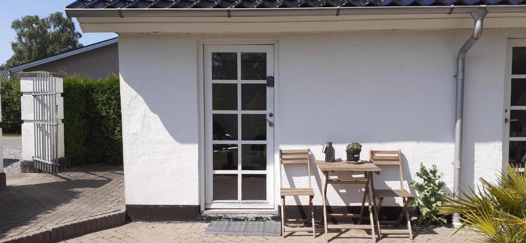 een wit huis met een tafel en stoelen op een patio bij Cozy tiny room, mini kitchen and bathroom in Otterup