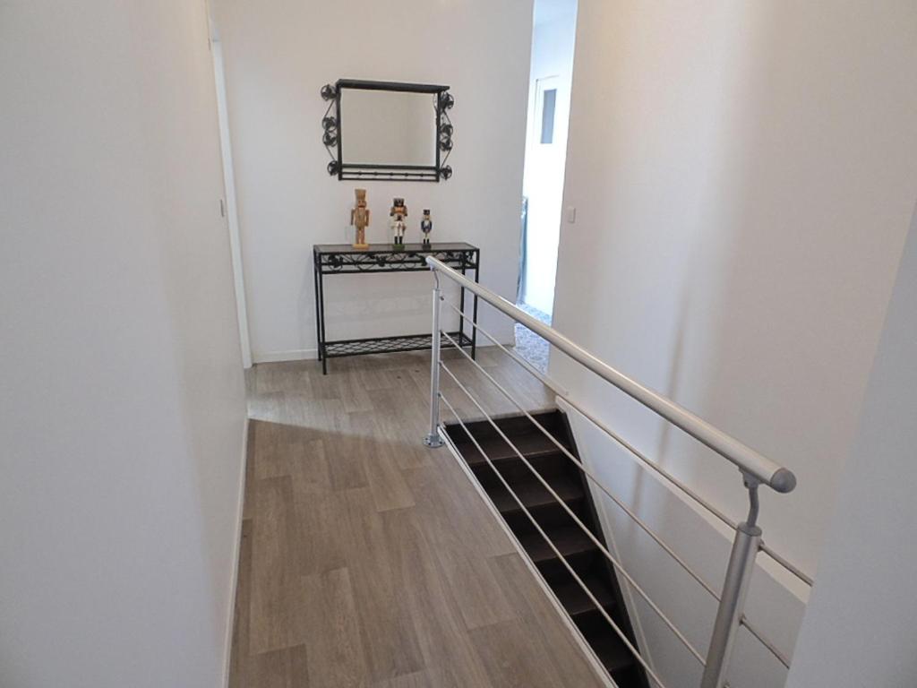 a hallway with a staircase with a mirror and a table at Le Coustalou in Puybrun