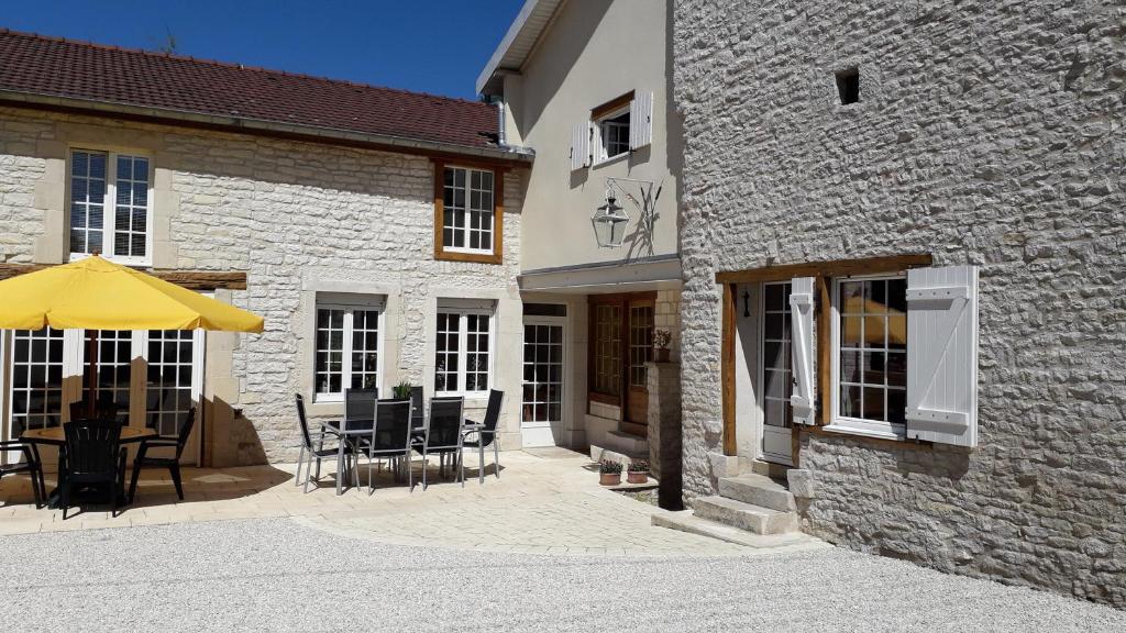 - une terrasse avec des chaises et un parasol à côté d'un bâtiment dans l'établissement Chez Madgi et Jean-Mi, à Froncles