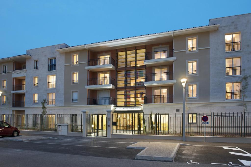 een appartementencomplex met een parkeerplaats ervoor bij Domitys Les Cigales du Lubéron in Cavaillon