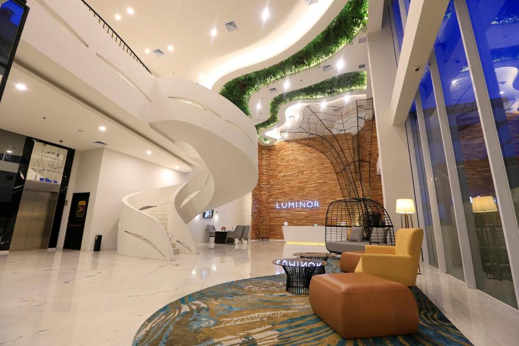 een lobby met een grote muurschildering van een boom bij Luminor Hotel Purwokerto By WH in Purwokerto