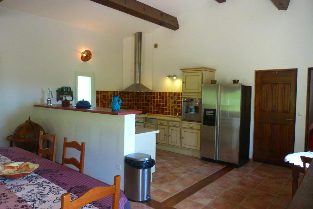 a kitchen with a stainless steel refrigerator and a table at Campagne SAINT MAURINET in Montmeyan