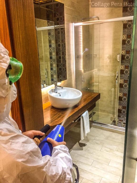 a person in a bathroom with a sink and a shower at Collage Pera Hotel in Istanbul