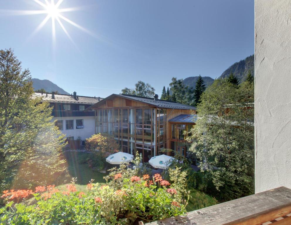 a view of a building with a yard with flowers at Outdoorhotel Jäger Von Fall in Lenggries