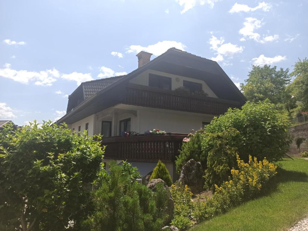 a white house with a balcony and bushes at Apartments Skok in Bled