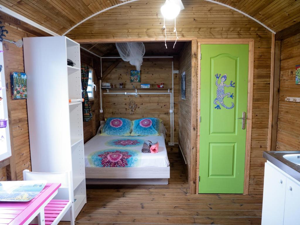 Kleines Zimmer mit einem Bett und einer grünen Tür in der Unterkunft La Roulotte De Tina in Le Moule