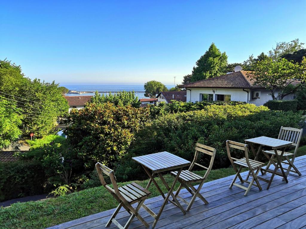 una mesa y sillas en una terraza de madera con vistas al océano en Les Digues Vauban, en Ciboure