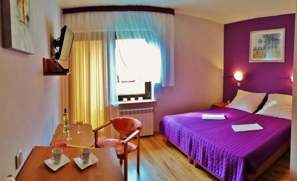 a hotel room with a purple bed and a table at Pokoje Gościnne Jantar in Łukęcin