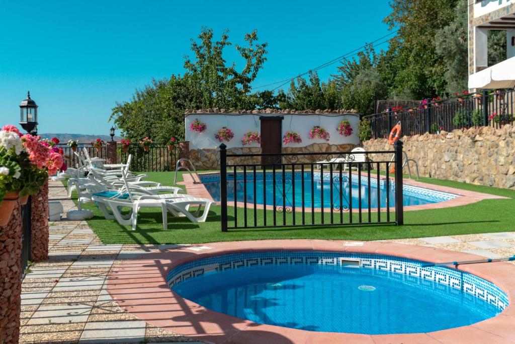 a pool with chairs and a table and a fence at Alojamientos Rurales Los Macabes in Alpujarra de la Sierra