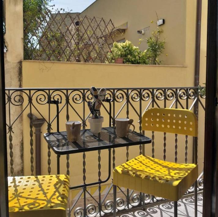 a table with two chairs and cups on a balcony at Casetta di Lele in Palermo